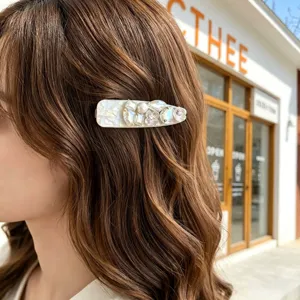 Detail shot of exquisite pearl and rhinestone hair clip worn on model hair, fashion accessory.