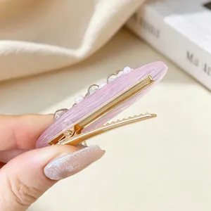 Detailed view of pink marbled hair clip with pearls and rhinestones, elegant side duckbill design.