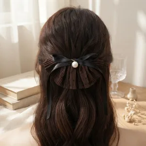 Retro brown polka dot hair clip with black ribbon bow and pearl detail, elegant half updo accessory.