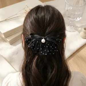 Detailed shot of retro sweet black polka dot bow hair clip with pearl pendant decoration.