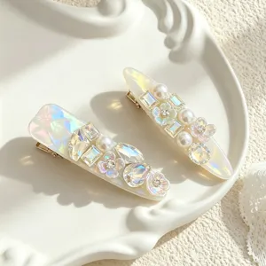 Close-up detail view of elegant pearl and crystal flower hair clips on white ceramic tray.