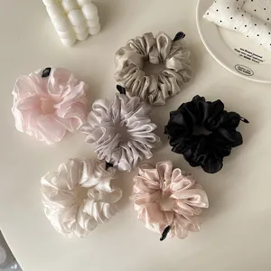 Detail view of fluffy pearl tulle hair scrunchies, showcasing soft pleated texture and multiple colors.