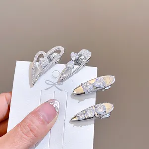 Close-up detail of silver sparkling zircon heart and bow hair clips, elegant duckbill clip design.