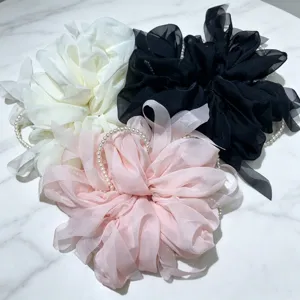 Gros plan d'élastiques à cheveux en maille perlée de style coréen blanc, noir et rose.