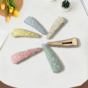 Detailed view of colorful crystal rhinestone hair clips arranged neatly on a white table surface.