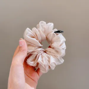 Detailed close-up of translucent shiny organza hair scrunchie, soft fluffy fabric design.