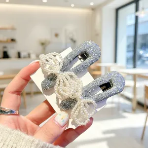 Close-up detail of silver glitter snap hair clips adorned with multi-layered pearl bow knots.
