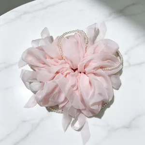 Vue detaillee chouchou cheveux rose en maille, attache elegante avec chaine de perles.