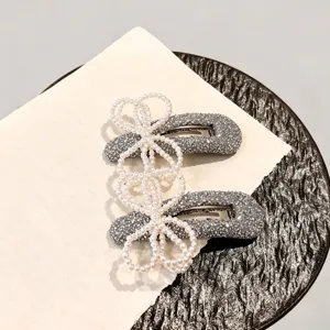 Detailed close-up view of sparkly silver BB hair clips featuring delicate pearl bow designs.