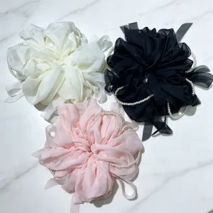 Vue détaillée des grands chouchous à cheveux en mousseline perlé blanc, noir, rose.