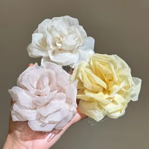 Detail shot of sweet organza camellia flower hair combs with pearls for charming hairstyles.