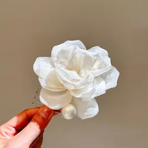 Close-up of white camellia pearl hair comb, elegant floral design with metal teeth detail.