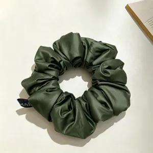 Gros plan détaillé de chouchou en satin vert foncé, montrant une texture plissée élégante.