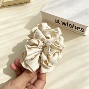 Elegant off-white fabric hair scrunchie detail shot, soft material ponytail holder accessory.