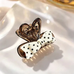 Close-up detail view of a brown translucent hair claw featuring a white polka dot bow.