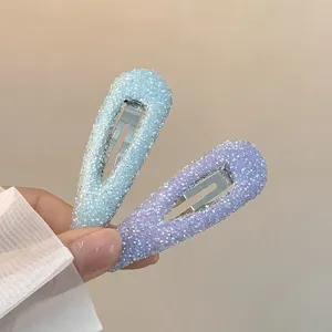Close-up detail shot of sparkling rhinestone waterdrop hair clips in pastel blue and purple.