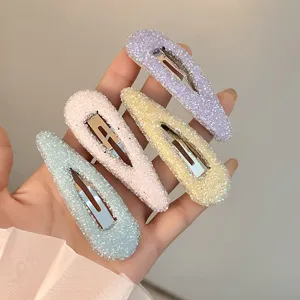 Close-up detail of pastel glitter waterdrop hair clips, sparkling rhinestones texture.
