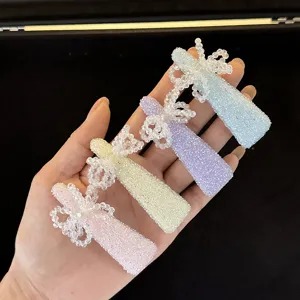 Close-up detail shot of pastel beaded bow hair clips, showing sparkling crystal texture and colors.