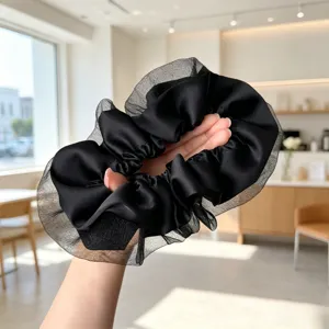 Vue détaillée du chouchou satin noir avec superposition de tulle transparent pour un style élégant.