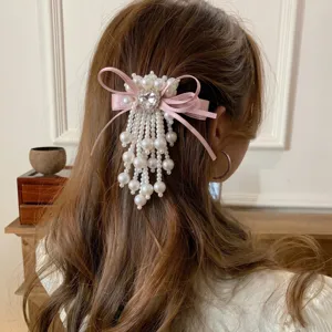 Closeup of Korean sweet pink bow pearl heart hair clip with elegant hanging tassel details.
