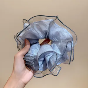 Close-up detail of the light blue organza hair scrunchie, showcasing fine sparkle texture.
