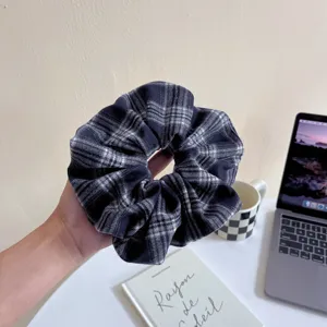 Detail view of a black and white plaid hair scrunchie, soft fabric elastic hair tie for women.