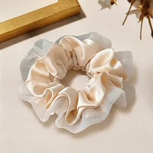 Gros plan détaillé d'un élégant chouchou en satin beige et dentelle, accessoire chic.