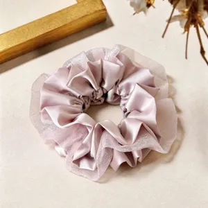 Détail de chouchou en satin et tulle rose exquis, accessoire de coiffure élégant.