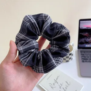 Close up view of the black and white plaid fabric hair scrunchie showing fine texture.