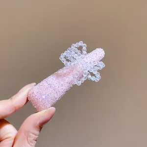 Pink crystal hair clip detail shot, sparkling rhinestone bow design, delicate accessory style.