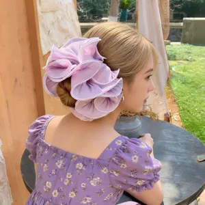 Close-up detail shot of the elegant purple ruffled hair scrunchie worn by a model.