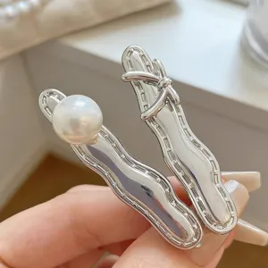 Silver metal hair clips detail featuring a glossy pearl and a cute bow, perfect for stylish bangs.