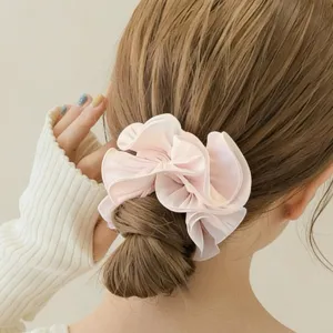 Detailed shot of a soft pink ruffled hair scrunchie, elegant lace design for cute buns.