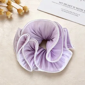 Details of elegant purple pleated hair scrunchie with white edge, soft elastic fabric.