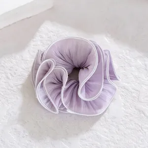 Close-up detail of the light purple pleated hair scrunchie showing fine fabric texture.