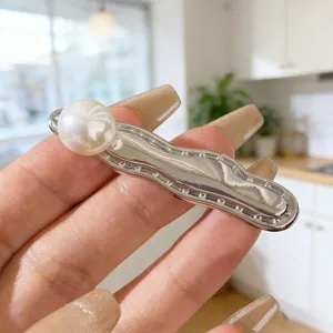 Close-up detail of the metal wavy hair clip with a elegant pearl decoration, perfect for bangs.