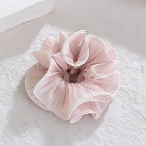 Close-up detail of soft pink ruffled hair scrunchie, elegant lace edge elastic hair band.