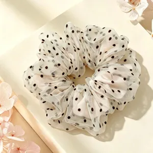Close-up of white mesh polka dot scrunchie, showing soft fabric and delicate black dots.