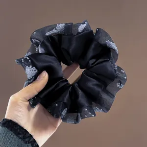 Close-up detail view of the black satin and sheer lace scrunchie with pearl details.