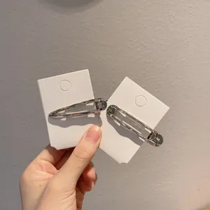 Gedetailleerde close-up van stijlvolle zilveren metalen haarspelden op kaart, ideaal voor trendy kapsels.