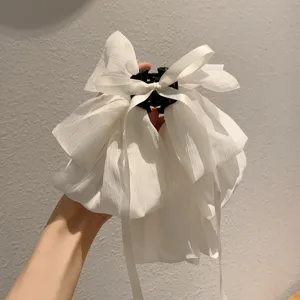 Detail shot of a white chiffon ribbon hair claw clip, featuring a large elegant bow design.