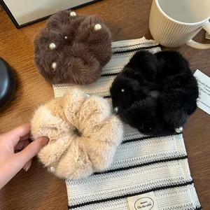 Dettaglio di morbidi scrunchies in peluche decorati con eleganti perle in vari colori chic.
