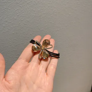 Crystal flower hair tie with champagne teardrop rhinestones and black elastic band for styling.