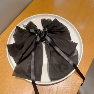 Detail view of a black chiffon bow hair claw clip with long ribbons for elegant ponytail styling.