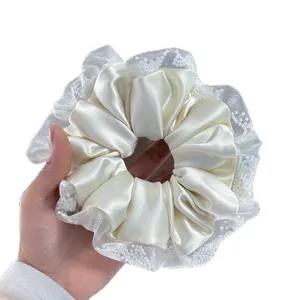 Elegant white satin scrunchie with delicate beaded lace trim, perfect for trendy hairstyles.