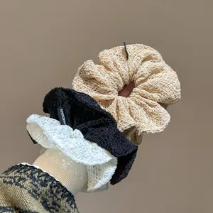 Primo piano dettagliato di morbidi elastici per capelli in maglia traforata in tre colori versatili.