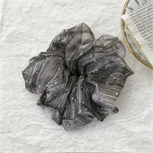 Gros plan détaillé sur un chouchou de cheveux en résine gris foncé avec pois blancs.
