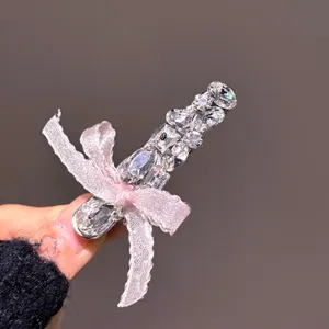 Close-up of a sparkling rhinestone dagger hair clip with a cute pink ribbon bow detail.