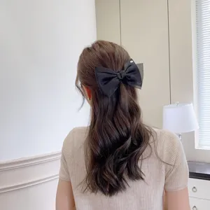 Detailed shot of a stylish black organza double-layer bow hair clip worn by a model.