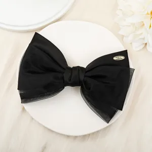 Detailed view of the elegant black double-layer organza bow hair clip with metal accent tag.